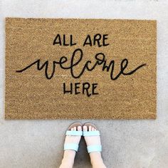 a person standing in front of a welcome mat that says, all are welcome here