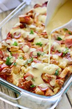 a casserole dish with ham, cheese and gravy being poured into it