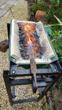 a large knife sitting on top of a grill with flames coming out of it's sides