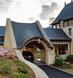 a car is parked in front of a house with an arched entrance and stone walls