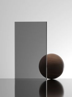 a ball sitting on top of a table next to a glass block with a reflection in it