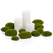 white candles surrounded by moss covered rocks on a white background with clipping for text