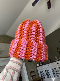 someone is holding up a pink and orange knitted mitt in the kitchen area