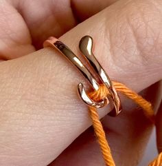 a person holding onto an orange rope with two scissors on it's end and one knot in the middle