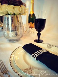 the table is set with black and white place settings, silverware, and champagne