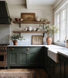 a kitchen with dark green cabinets and white counter tops, an open shelving above the stove