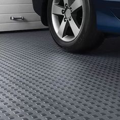 a blue car parked in front of a garage door with metal grates on the floor