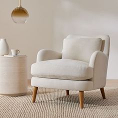 a white chair sitting on top of a rug next to a lamp and vases