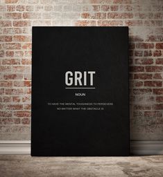 a black book sitting on top of a wooden floor next to a brick wall with the words grit written below it