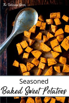 a pan filled with sweet potatoes on top of a wooden table next to a spoon