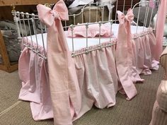 there is a crib with pink sheets and bows on it in the room next to other furniture