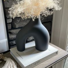 a black vase with some white flowers in it