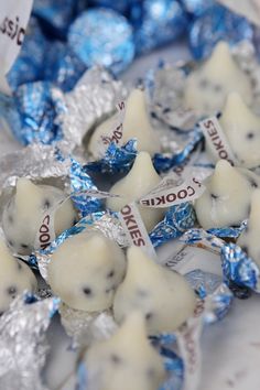 some white and blue candies are on a plate with foil wrappers around them