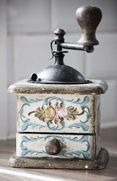 an old fashioned grinder sitting on top of a wooden table next to a tile wall