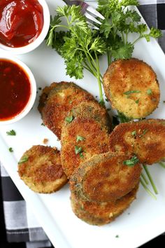 some fried food on a white plate with ketchup and sauces next to it