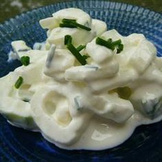 a blue plate topped with mashed potatoes covered in sour cream and green onion garnish