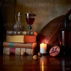 a candle and some books on a table with a pomegranate next to it