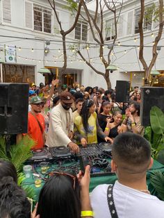 a group of people standing around a dj's set up in front of a crowd