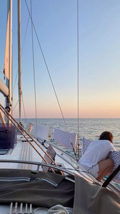 a woman is sitting on the deck of a sailboat