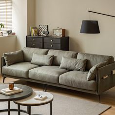 a living room with a couch, coffee table and side tables in front of a window