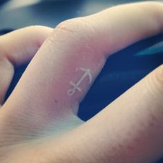 a person's finger with a small anchor tattoo on it