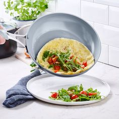 a person holding a pan with food in it over two plates on a counter top