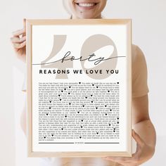 a woman holding up a framed poster with the words 50 reasons we love you