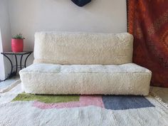 a white couch sitting on top of a rug in front of a wall mounted clock