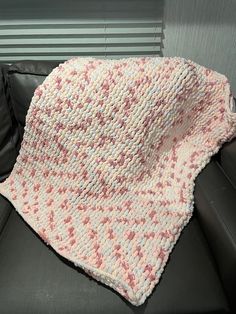 a crocheted blanket sitting on top of a black couch next to a window