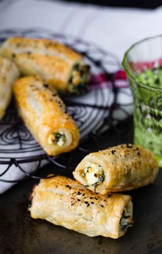 spinach and cheese pastries on a plate next to a glass of green tea