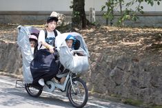 a man riding a bike with two children in the back