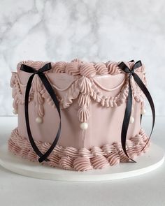 a pink cake with black ribbon on top