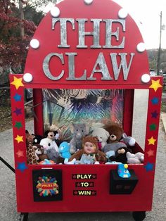 the claw game has stuffed animals in it and is red with silver letters that read, the claw