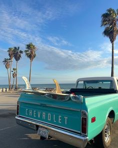 an old blue chevrolet pickup truck parked on the beach