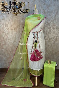 a green and white sari next to a chandelier with pink beads on it