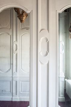 two white double doors with mirrors on the wall and one has a light fixture in it