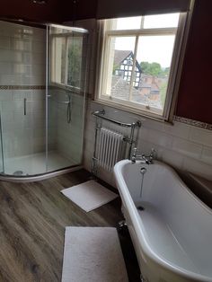 a bathtub sitting next to a window in a bathroom on top of a wooden floor