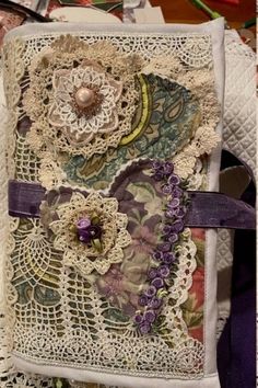 an altered book with lace and flowers on it