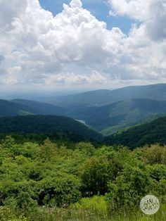 a scenic view of mountains and trees from the top of a hill with clouds in the sky