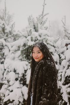 a woman standing in front of snow covered trees