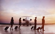 several people with suitcases are walking towards an airplane on the tarmac at sunset