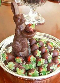 chocolate bunny sitting on top of strawberries in a bowl