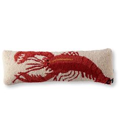 a red and white rectangular pillow with a lobster on it's side, sitting on a white surface