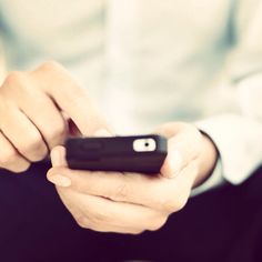 a close up of a person holding a cell phone in their hands and looking at the screen