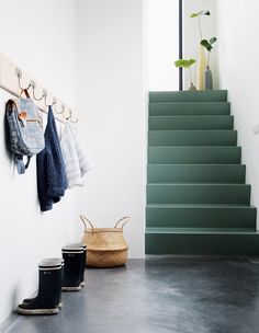 a set of stairs leading up to a hallway with shoes hanging on the wall and coat rack