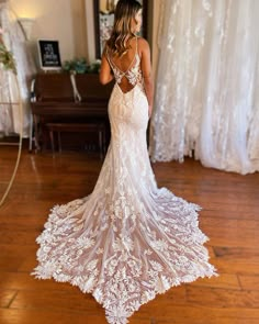 a woman standing in front of a piano wearing a wedding dress with an open back