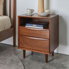 a nightstand with a book on it next to a bed