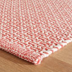 a red and white rug on top of a wooden floor next to a hardwood floor