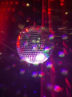 a disco ball hanging from the ceiling in front of bright colored lights and shadows on it