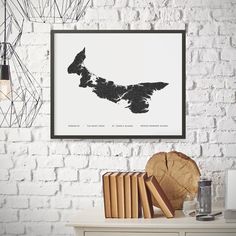 a white brick wall with a framed black and white map of new zealand